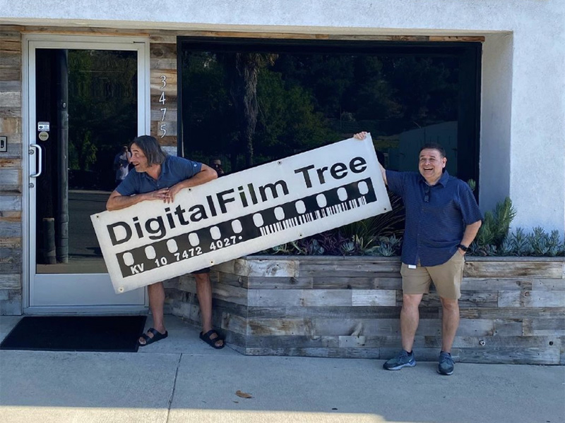 Ramy and Tim holding the old DFT sign while the new one goes up.